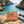 BiFi Chicken Roll 3-pack on a rock by a Mediterranean cove, with a towel and sunglasses, AI-generated image