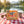 BiFi Chicken Roll 3-pack on a checked picnic blanket by a lake on a summer day, with a steel cup and sunglasses, AI-generated image