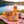 BiFi Starter Pack on a checked picnic blanket by a lake on a summer day, with a steel cup and sunglasses, AI-generated image