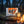BiFi Turkey 5-pack on a log by a campfire in a pine forest at dusk, with an enamel mug, AI-generated image