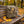 Biltong Premium Droëwors Original sticking out of a backpack on a park bench in autumn, with a water bottle and headphones, AI-generated image