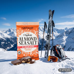 Chokay Bar Dark Almond Sea Salt in the snow next to touring skis and poles on a sunny winter day in the Alps, AI-generated image