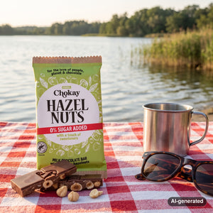 Chokay Bar Milk Hazelnuts on a checked picnic blanket by a lake on a summer day, with a steel cup and sunglasses, AI-generated image