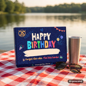 Happy Birthday Box on a checked picnic blanket by a lake on a summer day, with a steel cup and sunglasses, AI-generated image