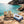 KJØ Mixed Pack on a rock by a Mediterranean cove, with a towel and sunglasses, AI-generated image