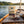 KJØ Spicy Beef Jerky on the deck of a small sailboat on a lake in the evening sun, with a rope and thermos, AI-generated image