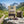 KJØ Teriyaki & Garlic Beef Jerky on a rock beside a mountain trail in the Alps, with a backpack and thermos, AI-generated image