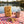 KoRo Banana Stripes on a checked picnic blanket by a lake on a summer day, with a steel cup and sunglasses, AI-generated image