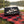 My Own Bundle Box on a checked picnic blanket by a lake on a summer day, with a steel cup and sunglasses, AI-generated image